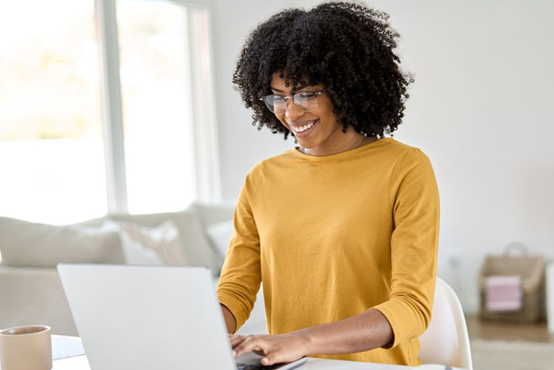 Woman in a yellow sweater working at a laptop